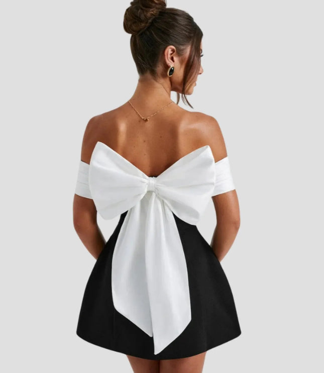 Back view of mini dress featuring dramatic white bow detail and off-shoulder design