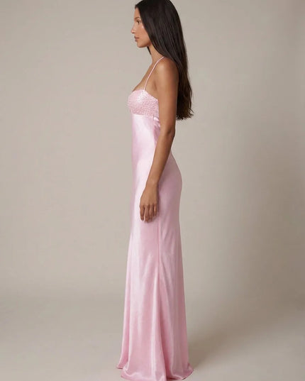 Side view of pink beaded halter maxi dress showing fitted satin shape and floor-length hem