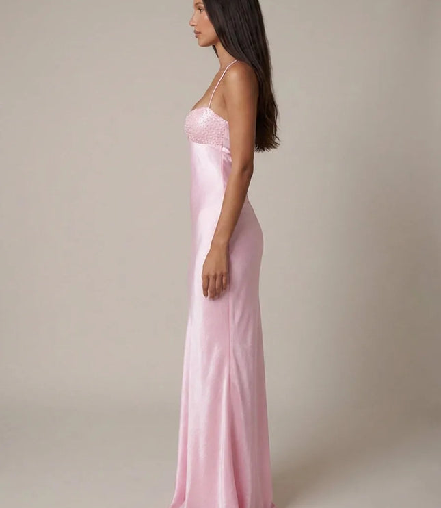 Side view of pink beaded halter maxi dress showing fitted satin shape and floor-length hem