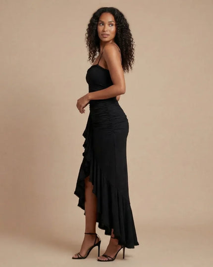 Side view of black spaghetti strap ruched maxi dress with asymmetrical hem