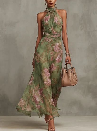 Women floral halter maxi dress in green with pink print, front view with flowing skirt and handbag