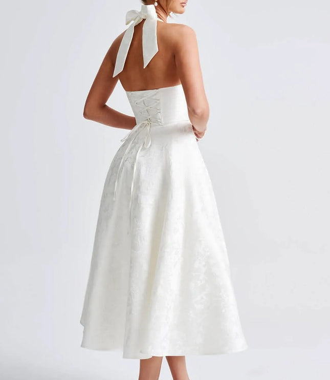 Back view of white floral halter midi dress with open back, bow tie neck, and lace-up waist