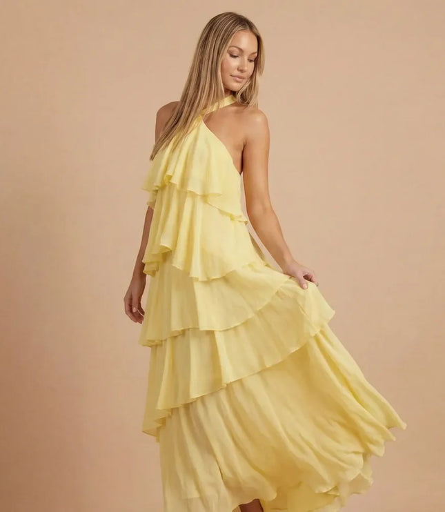 Yellow halter tiered maxi dress with flowing ruffled layers and asymmetrical hem
